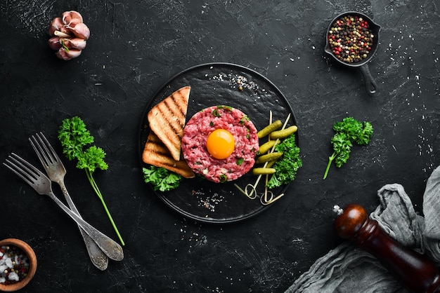 Beefsteak Tatar mit rohem Eigelb eingelegter Gurke und Zwiebeln Französische Küche Draufsicht Freier Platz für Ihren Text