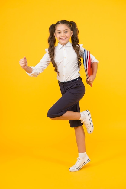 Beeilen Sie sich weitermachen Aktives Kind Mädchen mit Büchern auf dem Weg zur Schule Wissenstag Zurück zur Schule Kind fröhliches Schulmädchen läuft Schüler möchte lernen Aktives Kind in Bewegung Beginn der Schulstunde