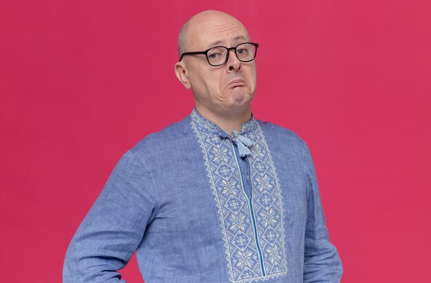 Beeindruckter erwachsener slawischer Mann im blauen Hemd mit Brille