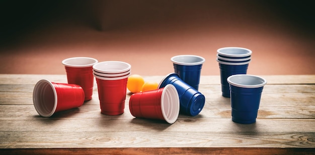 Beer pong Copos plásticos de cor vermelha e azul e bolas de pingue-pongue em banner de madeira