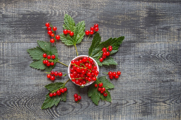 Beeren der roten Johannisbeere in einer Keramikschale auf einem rustikalen Holztisch