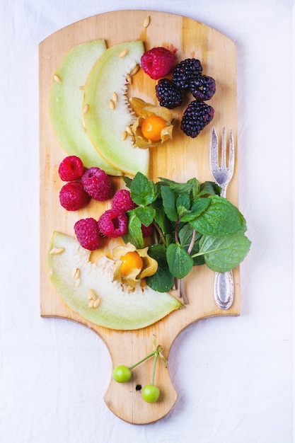 Beeren, Minze und Melone auf Holzbrett