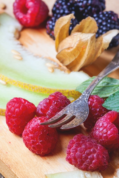 Beeren, Minze und Melone auf Holzbrett