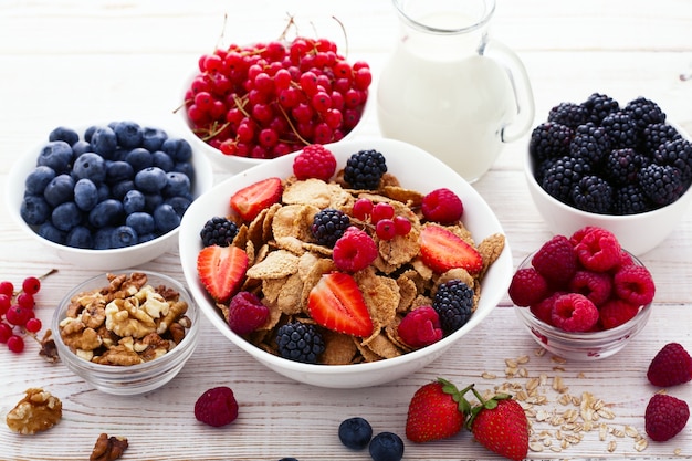 Beeren und Müsli in Teller mit Milch auf Holzschreibtisch