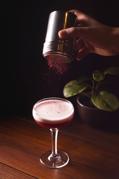 Beerenroter Cocktail mit Schaum in einem Glas auf einem dunklen Tisch