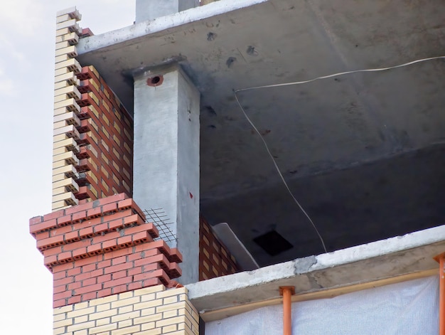 Befestigte Betonsäulen und monolithische Bodenplatten Außenmauer aus Ziegeln im Bau Ein Wohnhochhaus im Bau