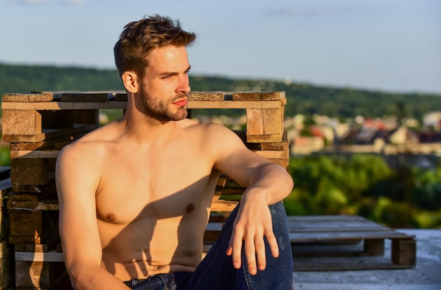 Befreien Sie Ihren Geist muskulöser Mann bei Sonnenuntergang Macho-Mann hat nackten Oberkörper sexy Mann in Jeans ausgezogen männliches Mode-Modell auf Himmelshintergrund Sommer entspannen sich im Freien sportlicher Sportler hat sexy Körper