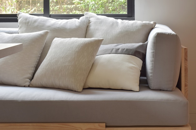 Bege varia almofadas de tamanho configuração no sofá confortável cinza claro