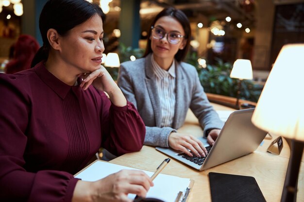 Begeisterte asiatische Frau, die an einem neuen Projekt arbeitet