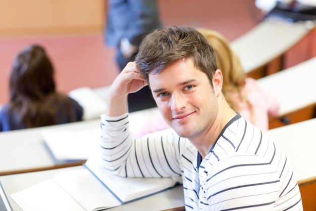 Foto begeisterter männlicher student, der an der kamera während einer universitätslektion lächelt