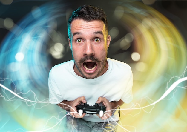 Begeisterter Spieler. Fröhlicher junger Mann, der einen Videospiel-Controller hält, der voller Emotionen ist, die auf buntem Hintergrund isoliert sind. Kaukasischer Spieler. Verrückt werden. Hat das schlechteste Team im Videospiel.