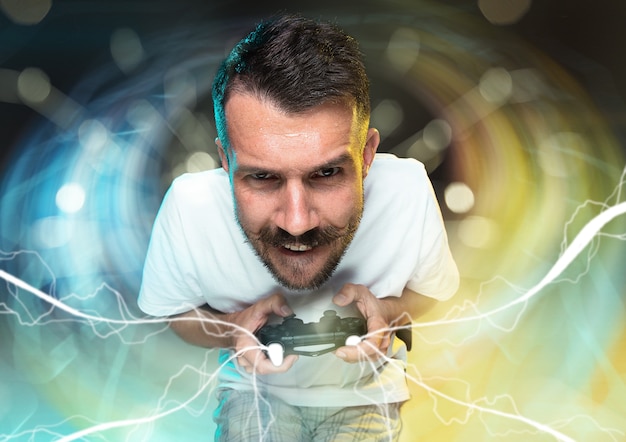 Foto begeisterter spieler. fröhlicher junger mann, der einen videospiel-controller hält, der voller emotionen ist, die auf buntem hintergrund isoliert sind. kaukasischer spieler. verrückt werden. hat das schlechteste team im videospiel.