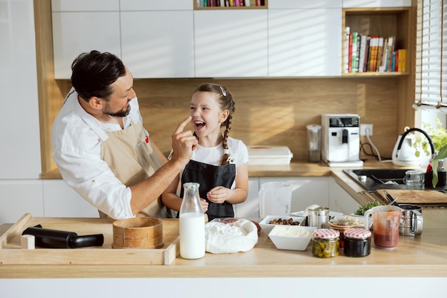 Begeisterter Vater, der die Nase der Tochter berührt und lacht, verbringt Zeit zusammen in der modernen Küche