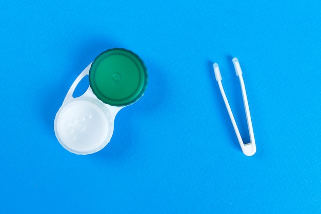 Behälter für Kontaktlinsen und Pinzetten auf blauem Hintergrund