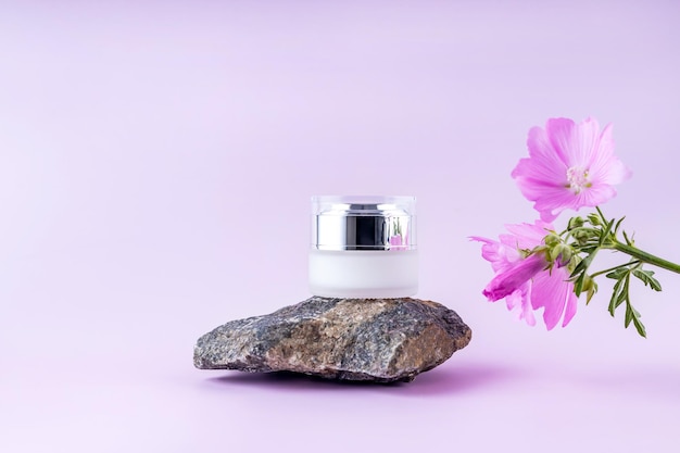Behälter für Kosmetiksteine und Blumen auf violettem Hintergrund