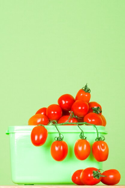 Behälter mit frischen Tomaten auf grünem Hintergrund