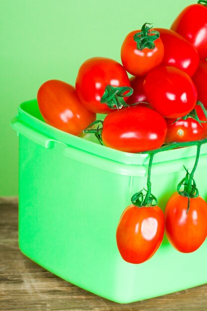 Behälter mit frischer Tomatennahaufnahme auf grünem Hintergrund