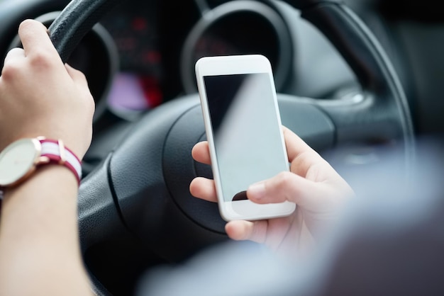 Behalten Sie die Straße im Auge und vermeiden Sie abgelenktes Fahren. Nahaufnahme eines nicht erkennbaren Mannes, der während der Fahrt sein Handy benutzt