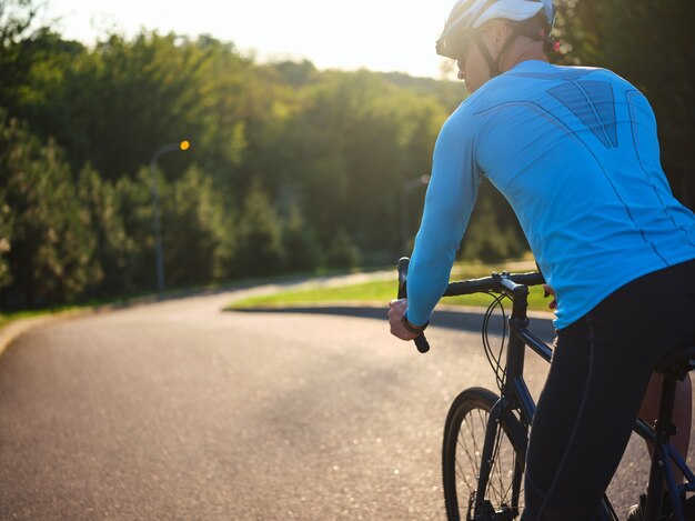 Behalten Sie eine gesunde Rückansicht des männlichen Radfahrers auf dem Rennradfahrer, der ein Fahrrad fährt, bei