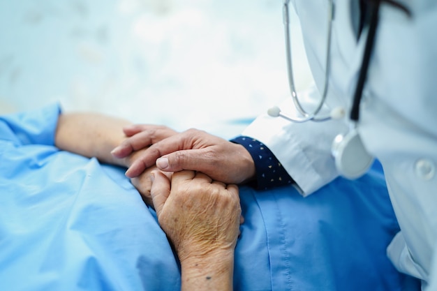 Foto behandeln sie das halten von rührenden händen asiatischen älteren oder älteren frauenpatienten der alten dame mit liebe, sorgfalt.