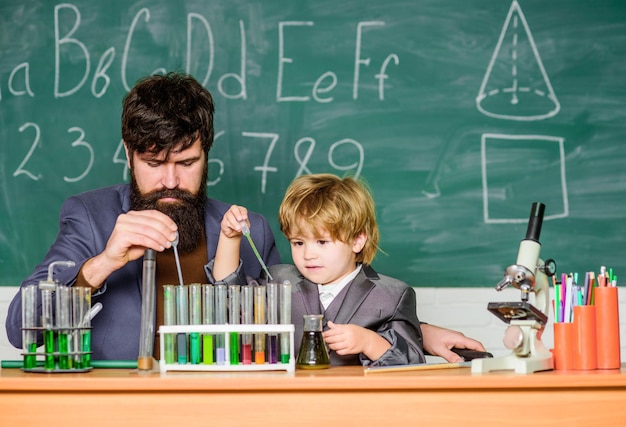 Beharrlichkeit zahlt sich aus. Chemisches Experiment. Symptome von ADHS in der Schule. Bildungsprogramm für die Schule. Niedliches Schulkind experimentiert mit Flüssigkeiten. Lehrer und Kinderreagenzgläser. Schulstunde