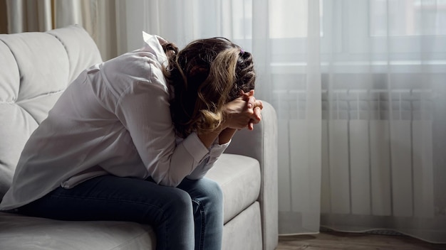 Behinderte Frau leidet unter Kopfschmerzen, die zu Hause auf dem Sofa sitzen