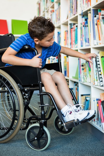 Behinderter Junge, der Bücher an Bibliothek sucht