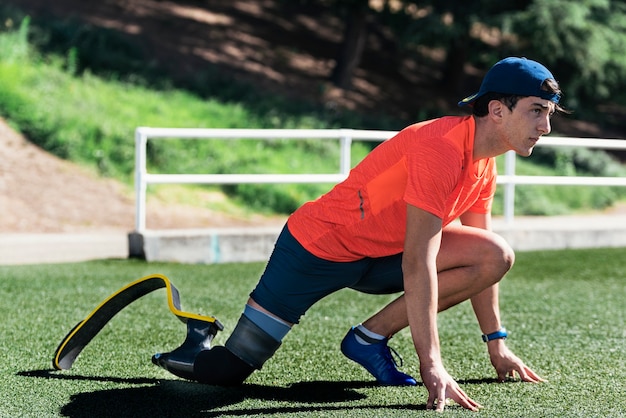 Behinderter Mann Athlet, der mit Beinprothese streckt. Paralympisches Sportkonzept.