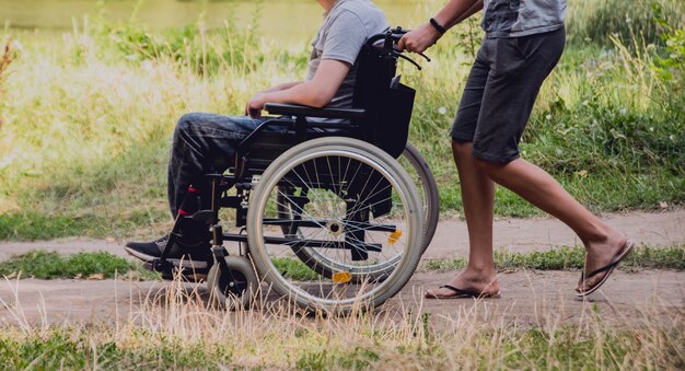 Behinderter Mann, der mit Freunden auf einem Campingplatz ruht. Rollstuhl im Wald