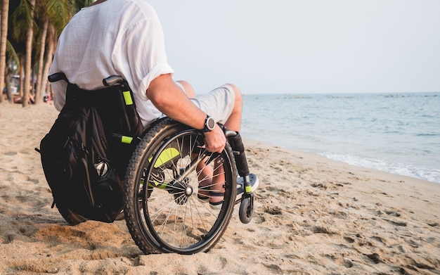 Behinderter Mann im Rollstuhl am Strand.