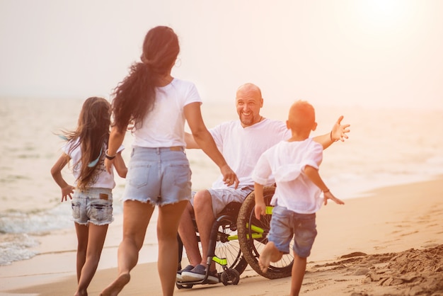 Behinderter Mann im Rollstuhl mit seiner Familie am Strand.