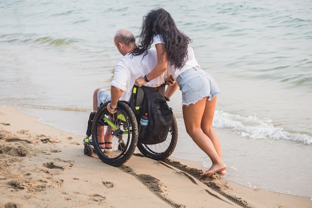 Behinderter Mann im Rollstuhl mit seiner Frau am Strand.