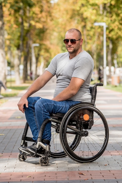 Behinderter Mann im Rollstuhlspaziergang an der Parkgasse