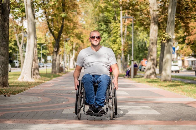 Behinderter Mann im Rollstuhlspaziergang an der Parkgasse