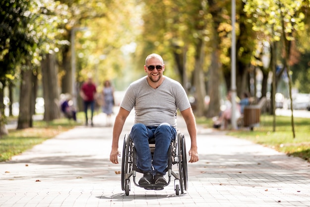 Foto behinderter mann im rollstuhlspaziergang an der parkgasse.