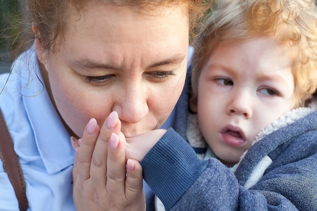 Foto behindertes kind mit einer mutter, die seine hand küsst. szene voller mütterlicher liebe.