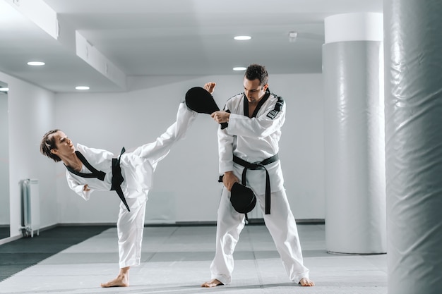 Behindertes Mädchen, das Taekwondo mit ihrem Training übt.