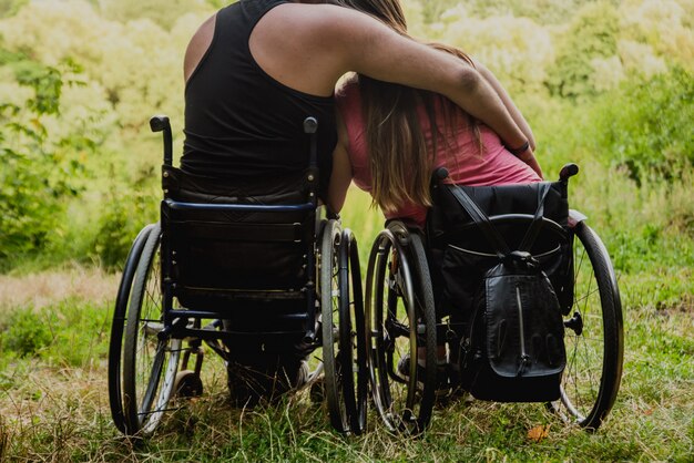 Behindertes Paar, das im Wald nahe See ruht. Rollstühle im Wald auf dem natürlichen Hintergrund