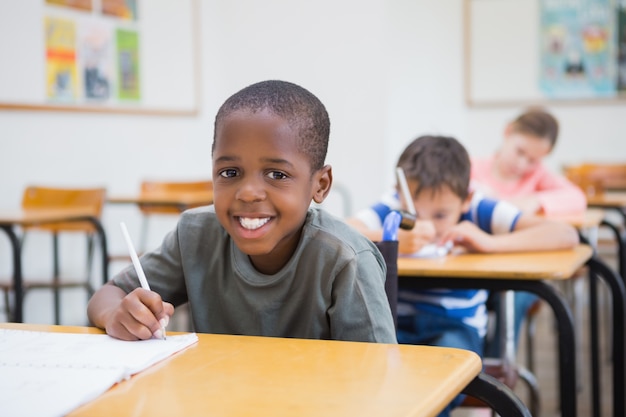 Behindertes Schülerschreiben am Schreibtisch im Klassenzimmer