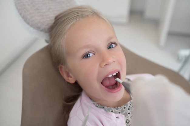 Bei den Zahnärzten. Kleines Mädchen sitzt mit offenem Mund beim Zahnarzt