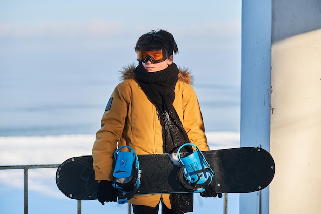 Bei strahlendem Sonnenschein posiert der junge Snowbordist mit seinem Snowboard für den Fotografen.