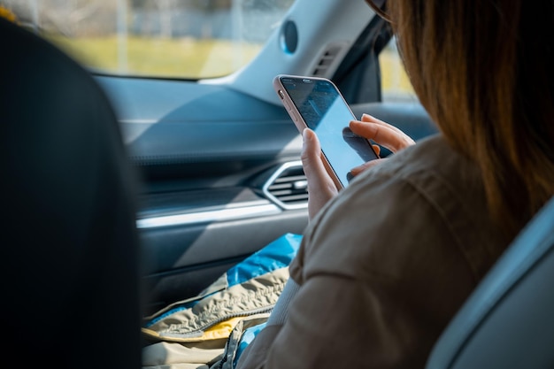 Beifahrerin, die mit dem Telefon im Auto sitzt