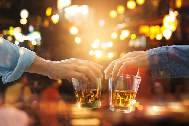 Beifall, der von den Freunden mit Bourbon Whisky trinkt, trinken in der Partynacht nach der Arbeit auf buntem