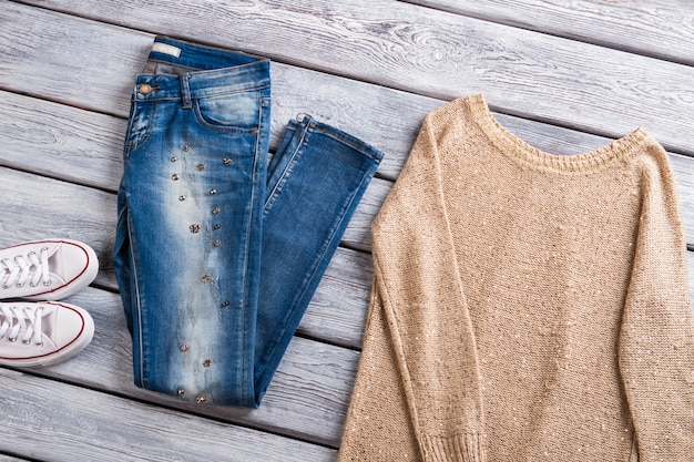 Beige Pullover und blaue Jeans weiße Segeltuchschuhe und Sweatshirt Freizeitbekleidung in Outlet-Shop-Qualität...