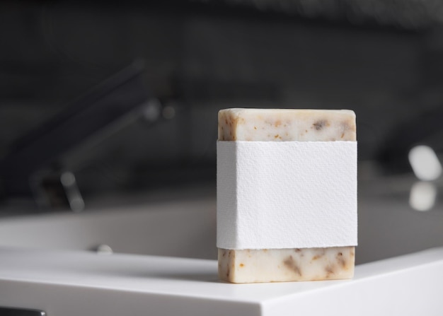 Beige Seife mit leerem Etikett auf dem Waschbecken in der Nähe des Wasserhahns in dunkelgrauem männlichem Badezimmer Close-up-Mockup
