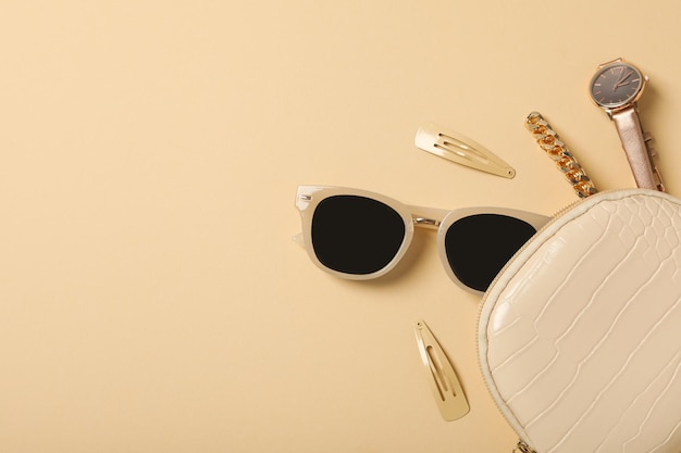 Beige Sonnenbrille mit weiblichen Dekorationen auf beige Hintergrund