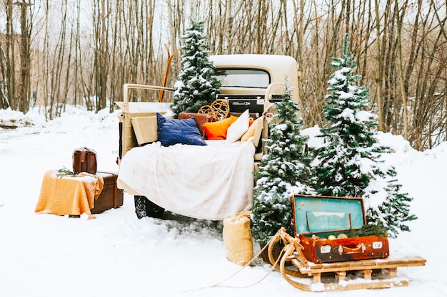 Beigefarbener Retro-Pickup-Truck, dekoriert für Weihnachten und Neujahr mit Vintage-Innenausstattung, Koffern, Skiern, Schlitten, Decken, Weihnachtsschmuck, Winterzeit