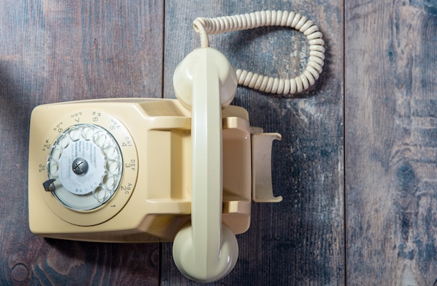 Beiges altes Telefon auf dem Holz