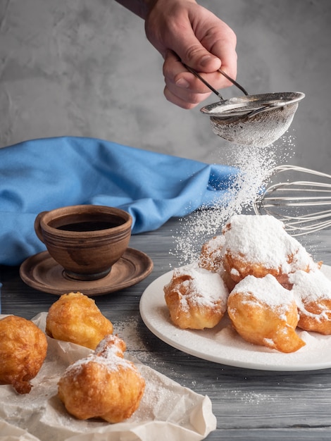 Beignet polvilhado com açúcar sobre uma mesa de madeira com café e leite.