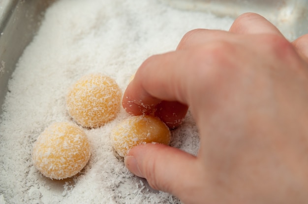 Foto beijinho de coco a mão fazendo um doce tradicional brasileiro